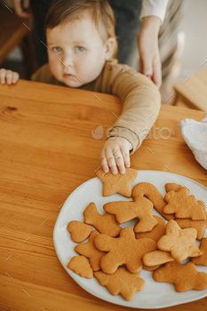 Cute little girl grabbing freshly baked gingerbread cookie on wooden table in modern room / Photodune, Misc