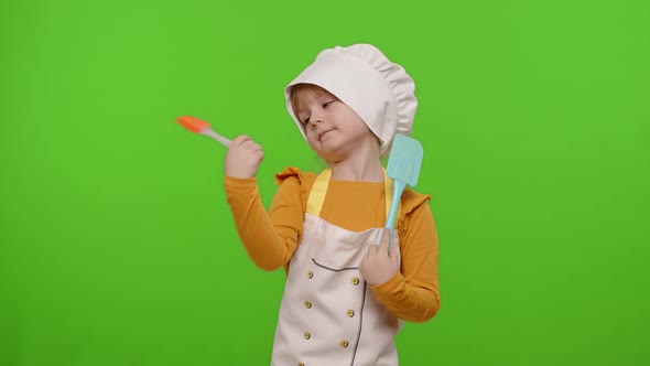 Funny Child Girl Kid Dressed Cook Chef Baker in Apron and Hat Dancing Fooling Around Making Faces