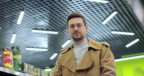 Portrait of Young Man in Glasses Standing in Big Supermarket