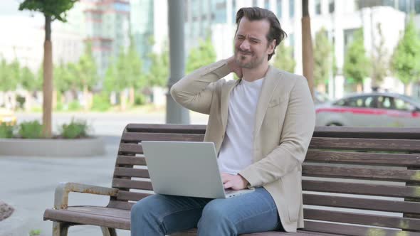Young Man with Neck Pain Using Laptop While Sitting on Bench