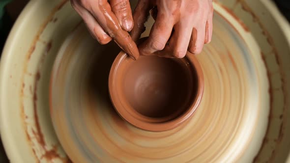 Top view of the potter's work. Hands masterfully work a clay pot