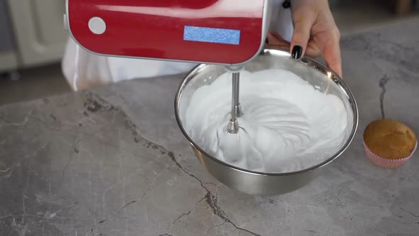 Female Baker Using Motor Mixer for Mixing white Egg Cream in Bowl