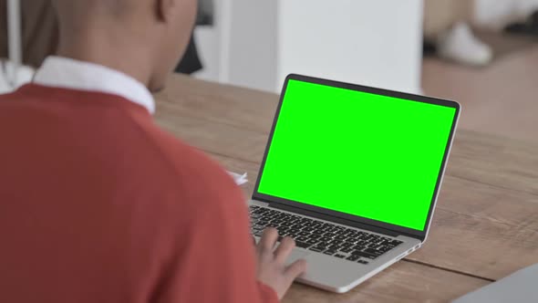 Rear View of African Man Working on Laptop with Green Chroma Screen