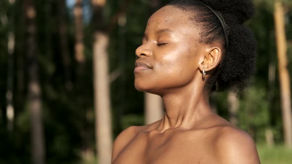Calm Young Black Woman Taking a Deep Breath of Fresh Air, Relaxing, Meditating with Her Eyes Closed