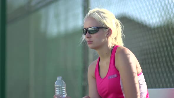 A tennis player drinking water between matches