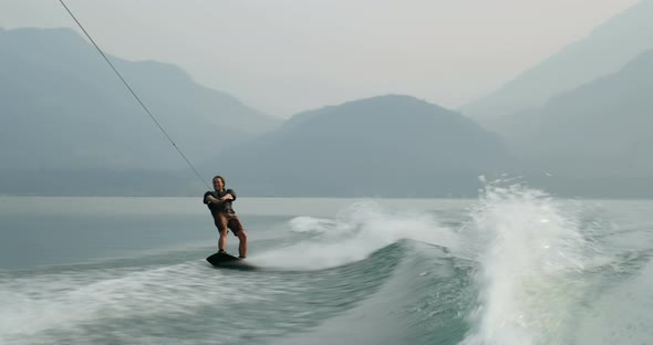 Front view of caucasian young man doing tricks on wakeboard in the city river 4k