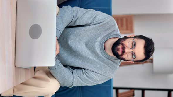 VERTICAL VIDEO POV Smiling Freelancer Hispanic Man Sitting on Couch in Front of Laptop