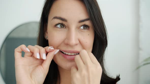 Smiling Girl Taking Care of Teeth Using Dental Floss During Morning Activities in Bathroom