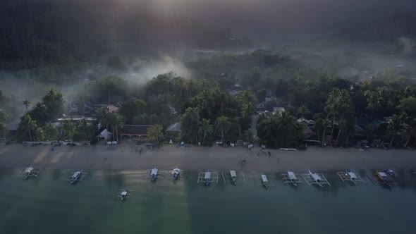 Aerial of misty morning in beautiful fishing village by the beach in the Philippines - camera pedest