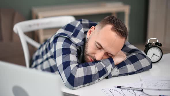 Tired Employee Sleeping on Desk Surrounded By Laptop and Documents