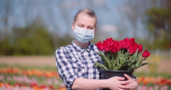 Woman Holding Tulips Bouquet in Hands While Walking on Tulips Field