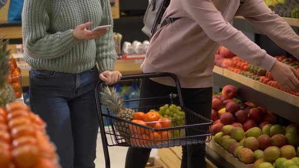 Young Couple Filling Shopping Cart in Supermarket