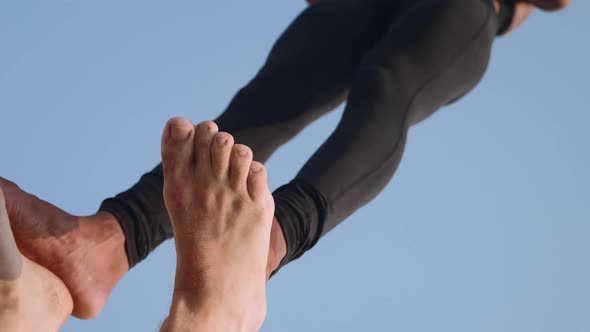 Fit Sporty Couple Practicing Acro Yoga with Partner Together on the Sandy Beach.