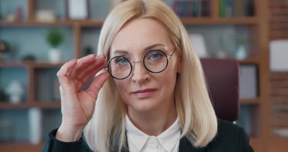 Smiling Confident Blond Businesswoman in Glasses Posing on Camera on Modern Office Room