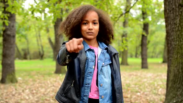 Young African Happy Girl Show with Finger on You and Nod Her Head - in the Park