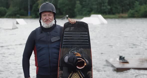 Wakeboarder, Portrait of Adult Man, Sportsman Stands Near the Lake, Looks at the Camera and Holds a