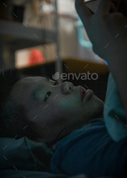 Man sitting in bed looking at his phone / Photodune, Misc