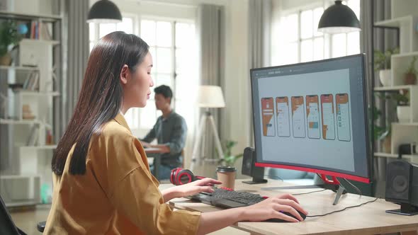 Asian Female Mobile Application Developer Works With Graphics On Her Personal Computer In Office