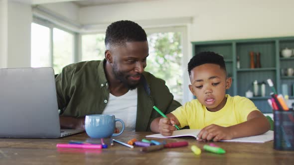 African american father and son doing homework and using a laptop together