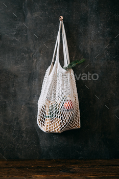 tmas. Eco friendly mesh net shopping bag with craft gift boxes and green fir tree branch. Mesh Reusable Cotton Grocery Bag with Christmas gifts.