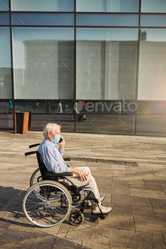 a wheelchair while talking on the smartphone outdoors