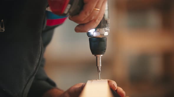 Carpentry Industry - Man Worker Drills Screws Into the Wooden Plank