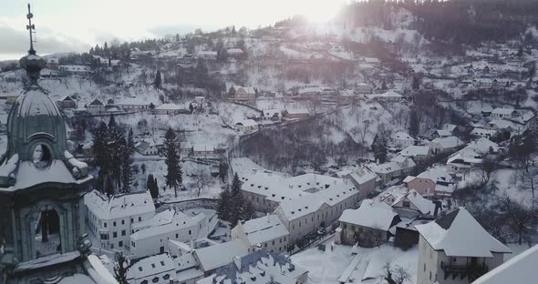 Flying backwards and revealing Old Castle tower covered by snow in Mining town Banska Stiavnica, Aer