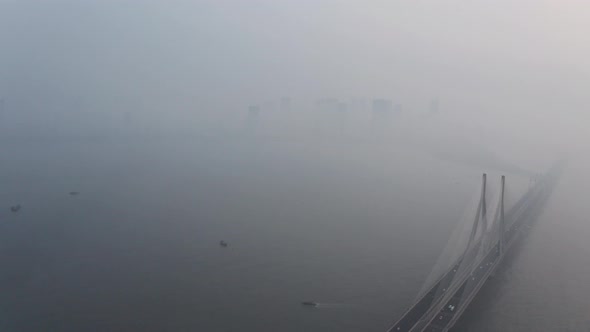 Dolly back drone shot of Mahim bay Mumbai sealink bridge on a hazy polluted day