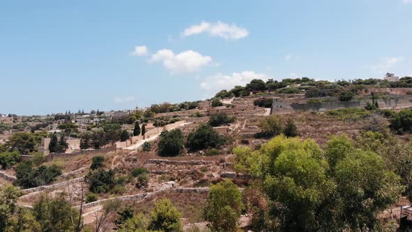 Rising aerial view of Malta island rural fields on sunny summer day from Top of the World, Gharghur