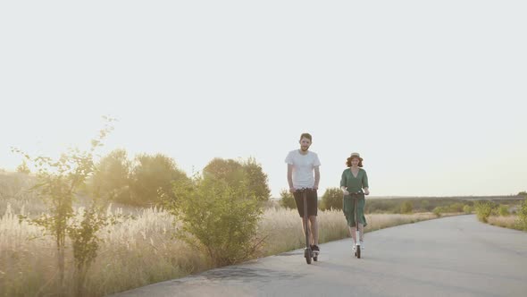 Couple in Love Riding on Electric Scooters with Joy on the Asphalt Road