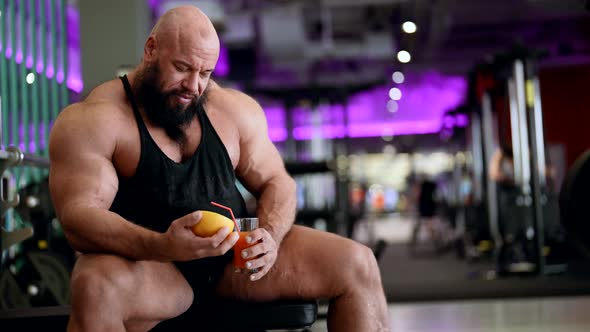 Professional Sportsman is Drinking Grapefruit Juice in Gym After Training Muscular Powerlifter