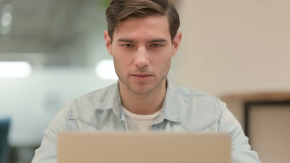 Close Up of Creative Young Man with Laptop Smiling at Camera