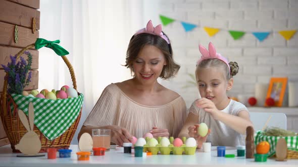 Beautiful Mother and Daughter Packing Dyed Easter Eggs Into Box High-Fiving