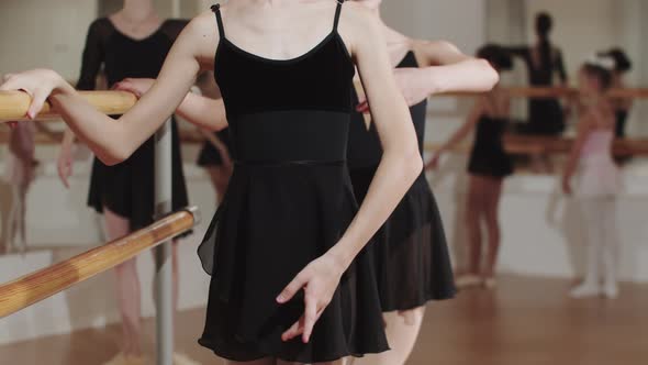 Two Little Girls Training Near the Stand in the Ballet Studio