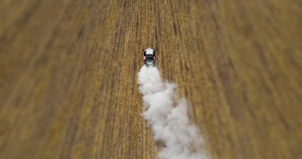 A Tractor Drives Fertilizer Across A Mown Field 