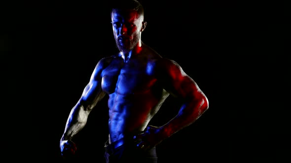 a Man with a Muscular Naked Torso and Goldenmetallic Skin Poses Under Water Drops on a Black