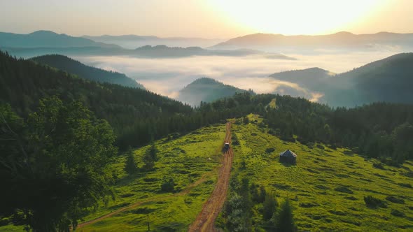 Aerial Flight Over the Road in the Mountains Leading to a Valley Covered with Fog