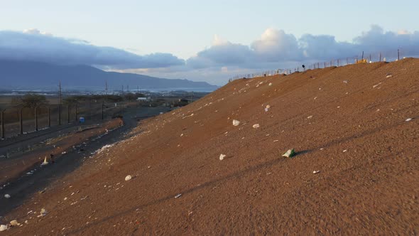 Close Up Remaining Plastic Waste Flying with Wind By Landfill Slope at Sunset