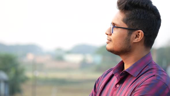 Thoughtful Young Man Hand Over Head Looking Away in Nature