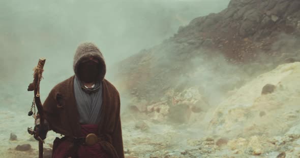 Hooded Man Passing Through Misty Landscape