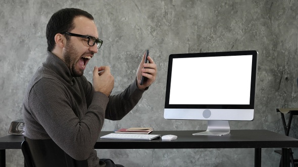 Man checking his teeth in the office near computer screen