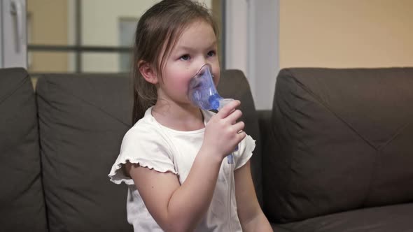 Little Girl Does Inhalation with a Mask on Her Face at Home