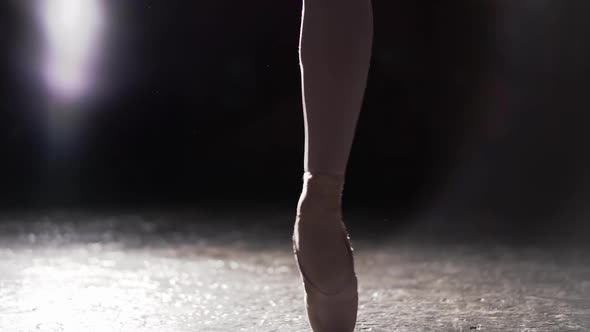 Graceful Ballerina Dancing on Her Pointe Ballet Shoes in Spotlight on Black Background in Studio