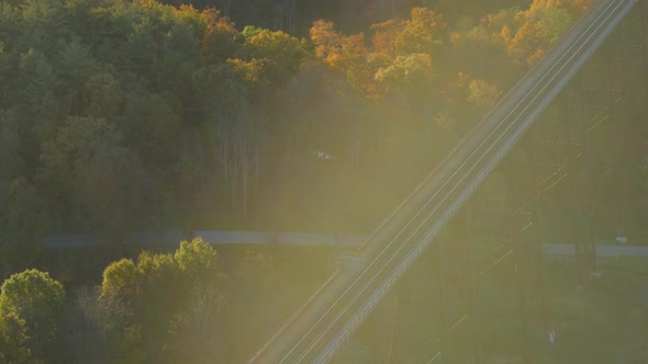 Aerial of railroad bridge passing over autumn forest in valley