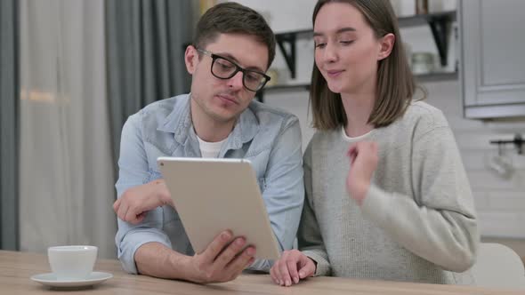 Attractive Young Couple Using Tablet in Living Room 