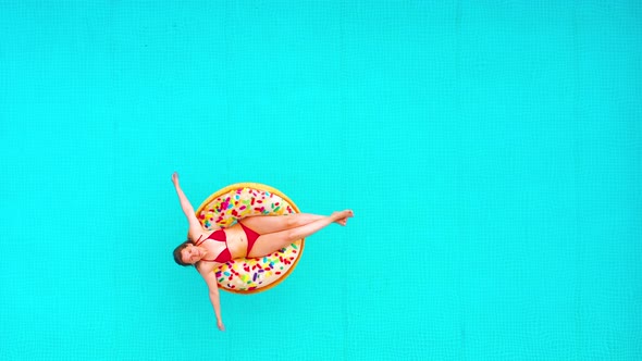 Aerial View of a Woman in Red Bikini Swimming on a Donut in the Pool