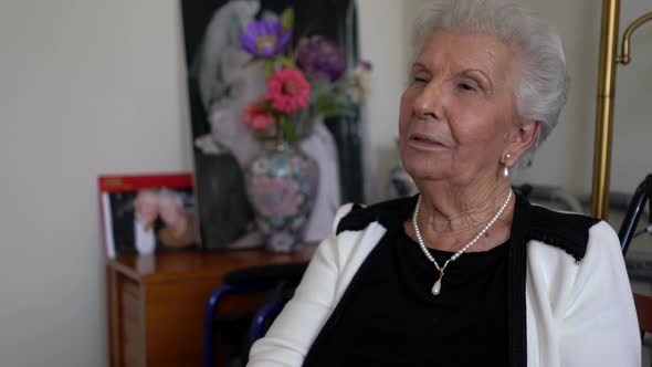 Closeup of elderly woman sitting and talking and laughing and smiling.