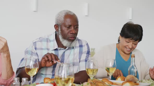 Happy senior diverse people having dinner at retirement home