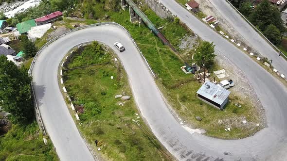 Aerial Rotating Shot of Vehicles Passing Through a Curvy Himalayan Road
