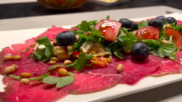 Static close up of delicious served dinner with fresh raw beef with salad,tomato,blueberry and pine